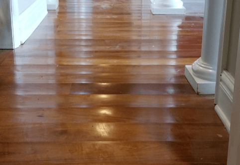 Timber floorboards showing cupping due to water damage, with a visibly uneven surface.