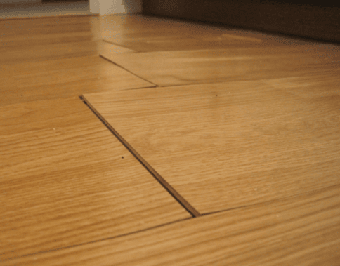 Floorboards with misaligned edges and gaps caused by moisture damage